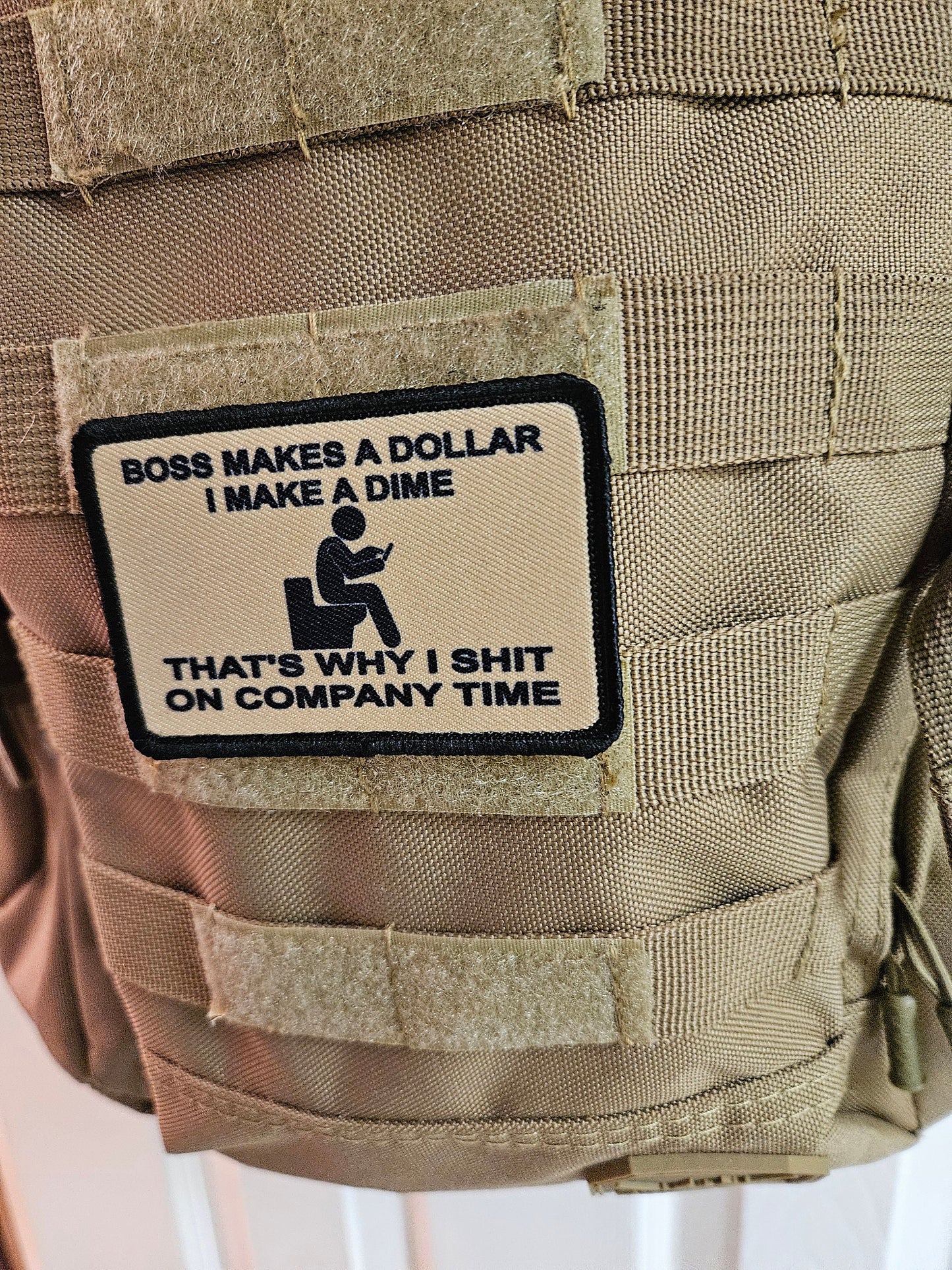 Boss makes a dollar I make a dime that's why I shit on company time 2"x3" morale patch with hook and loop backing tan