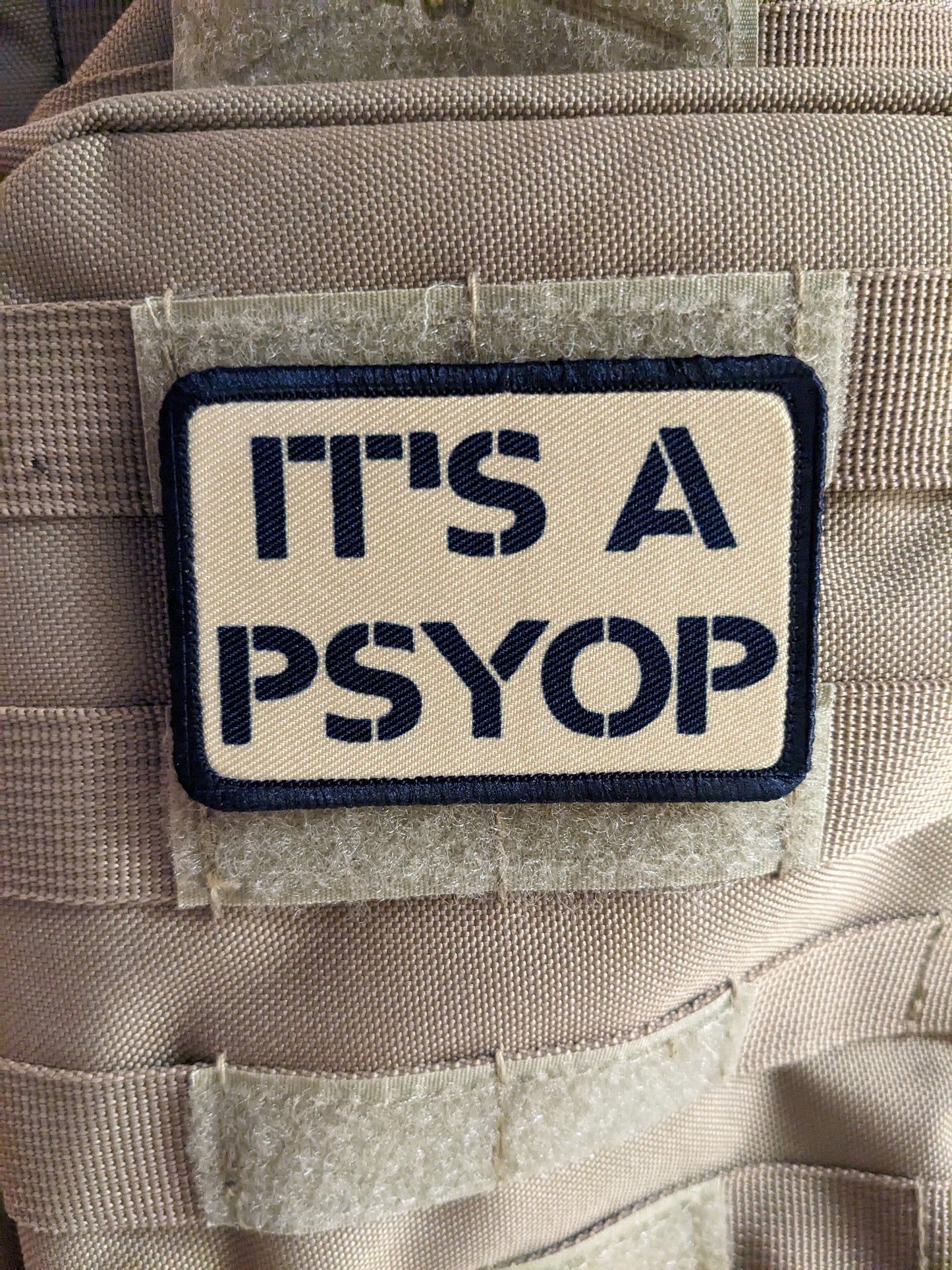 It's a Psyop conspiracy joke tan 2"x3" morale patch with hook and loop backing