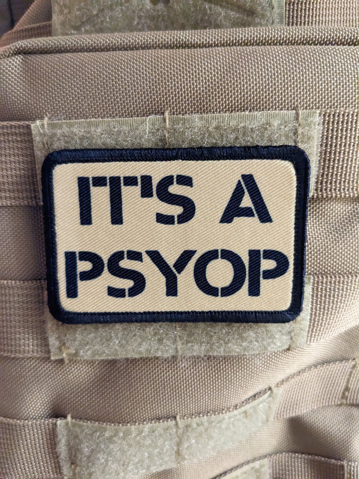 It's a Psyop conspiracy joke tan 2"x3" morale patch with hook and loop backing