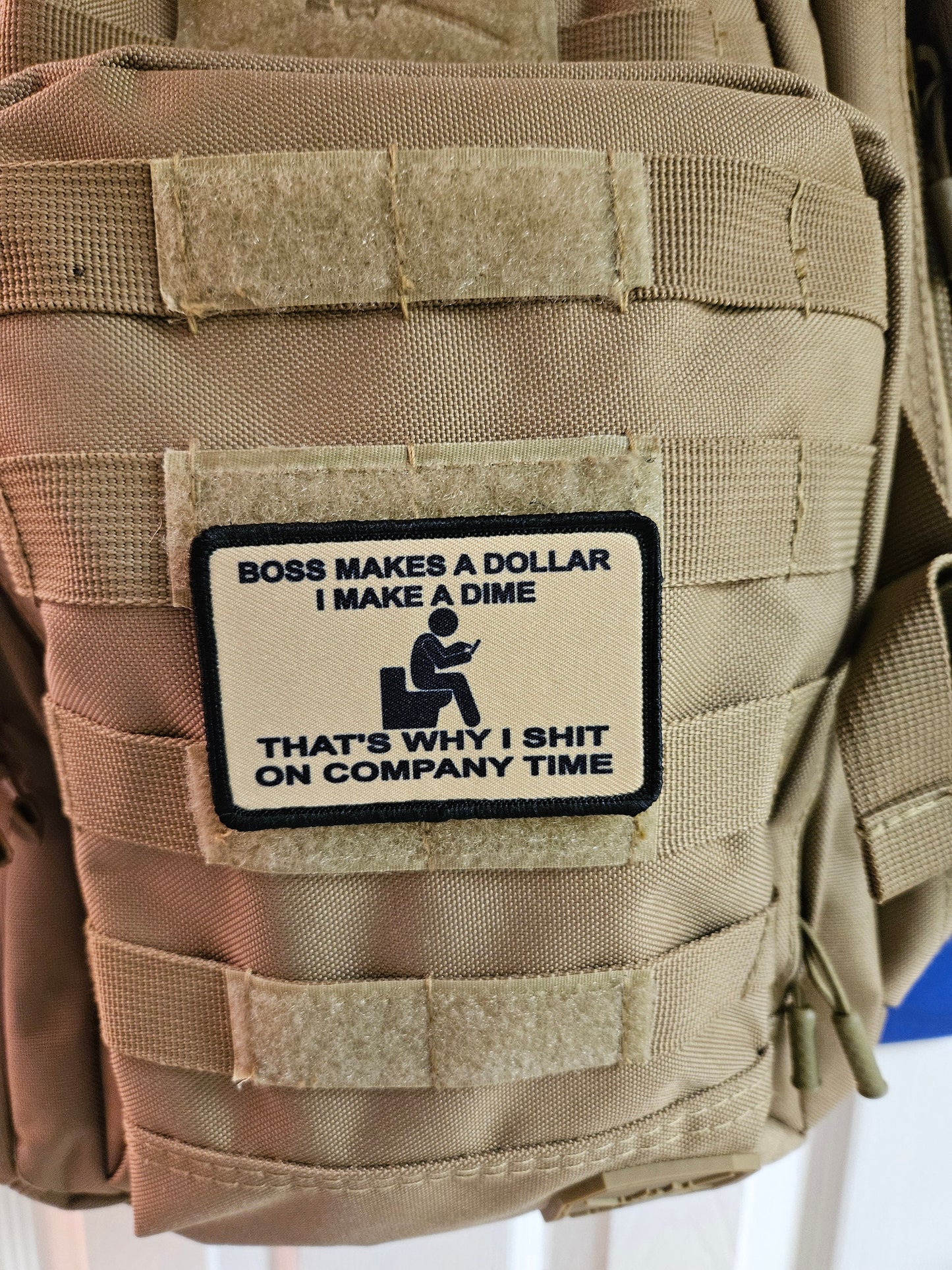 Boss makes a dollar I make a dime that's why I shit on company time 2"x3" morale patch with hook and loop backing tan