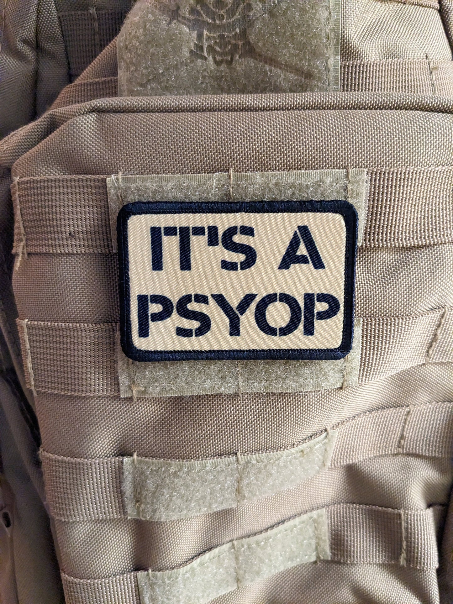 It's a Psyop conspiracy joke tan 2"x3" morale patch with hook and loop backing