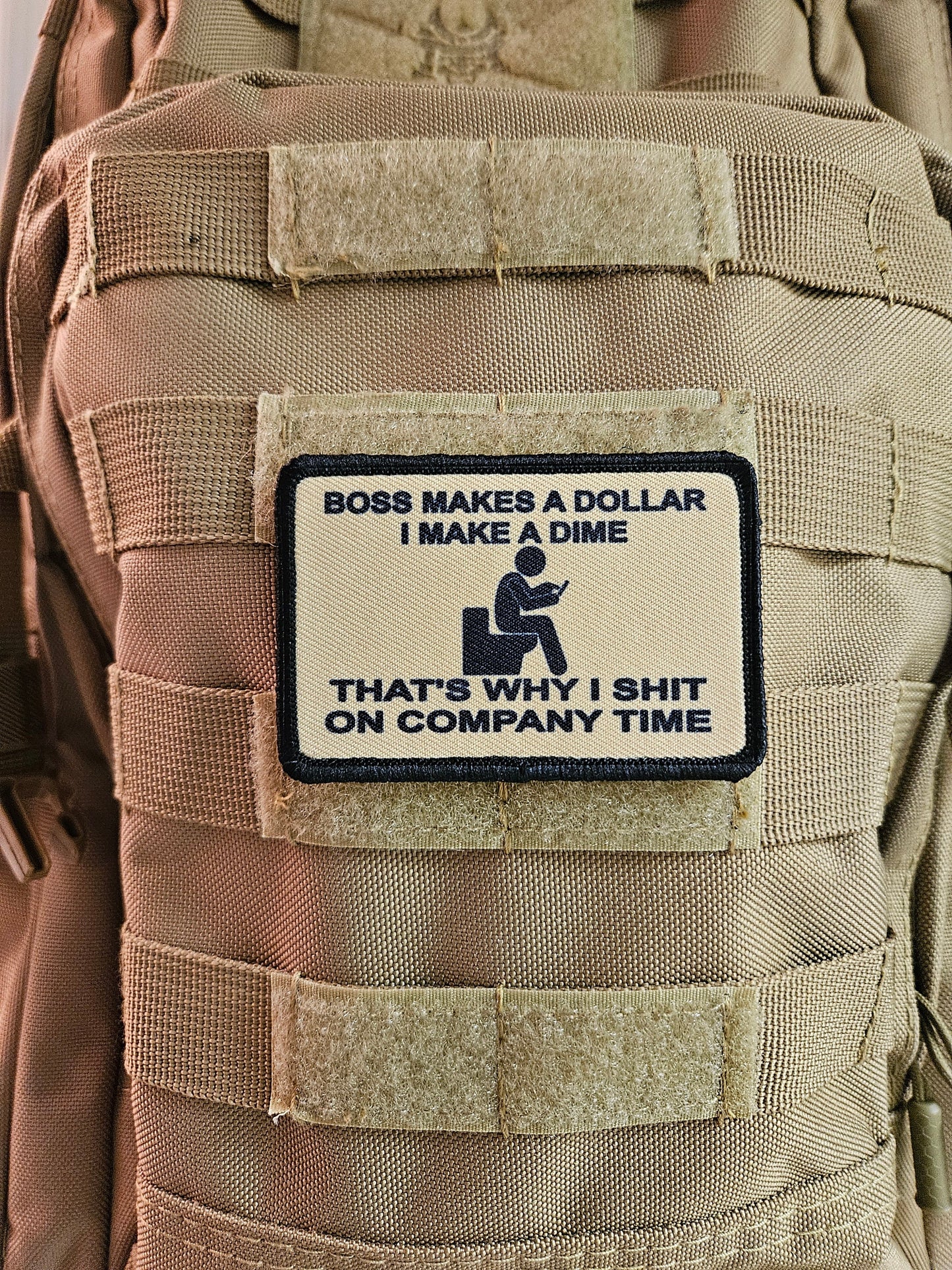 Boss makes a dollar I make a dime that's why I shit on company time 2"x3" morale patch with hook and loop backing tan